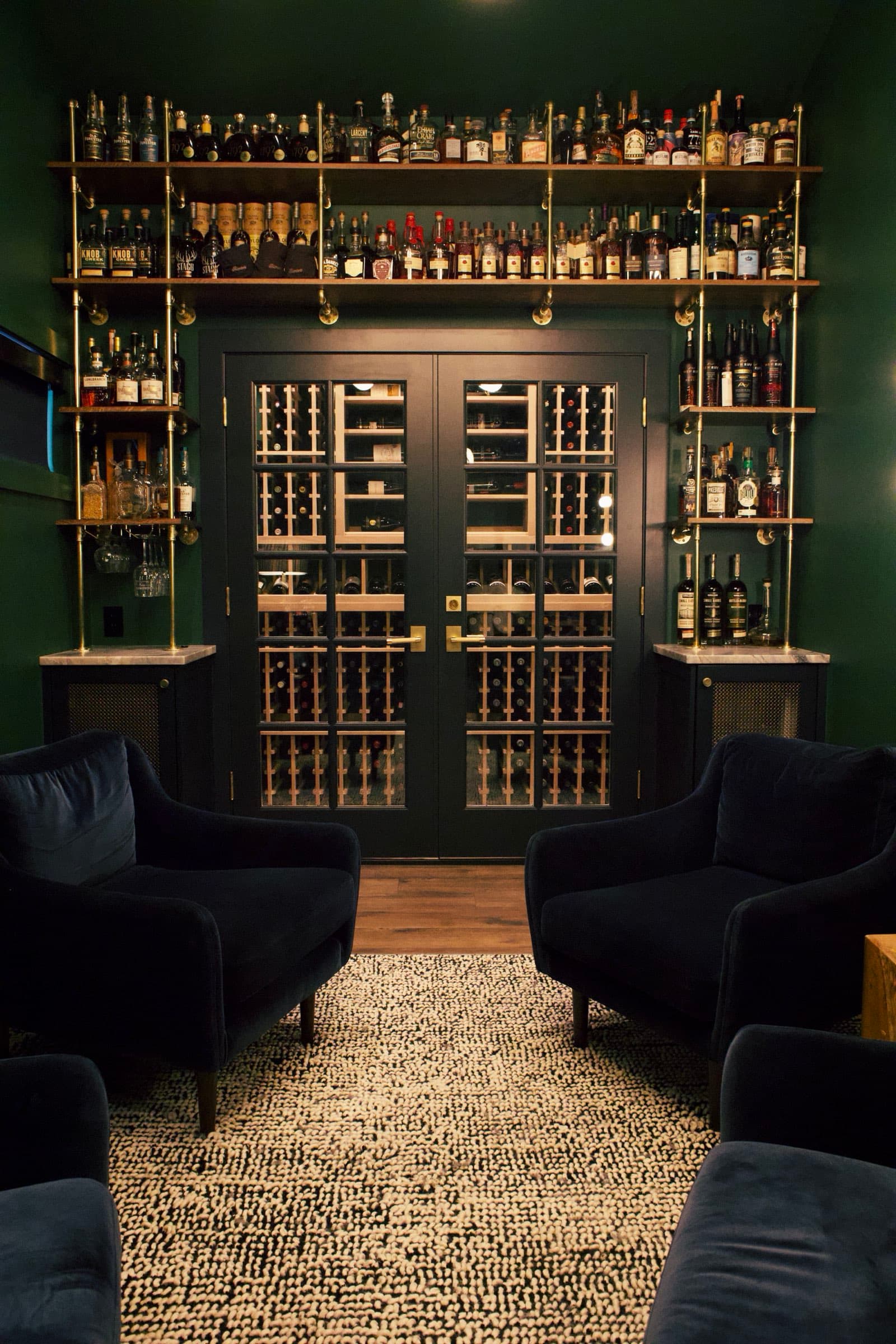The bar wall — brass shelving, whiskey bottles, and wine cellar behind glass doors