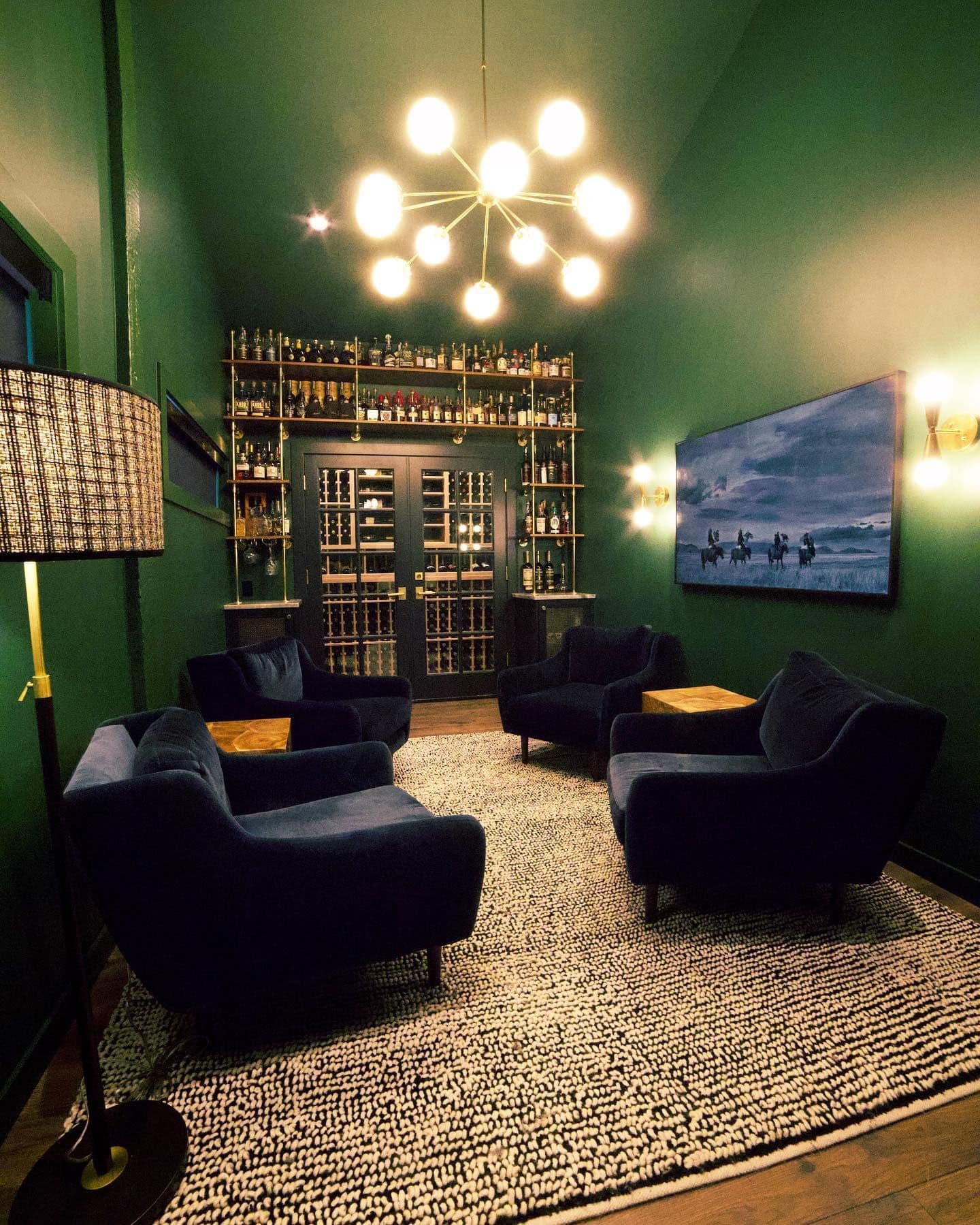 The finished room — chandelier, Frame TV, velvet chairs, sconces, and the full bar wall