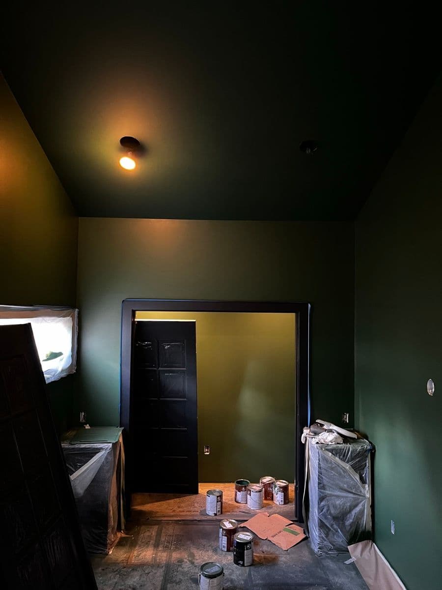 Sconce casting warm light on green wall, cellar visible through the doors